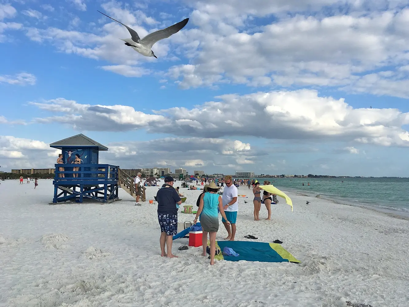 Blue lifeguard stand and visitors on the white sand at Coquina Beach