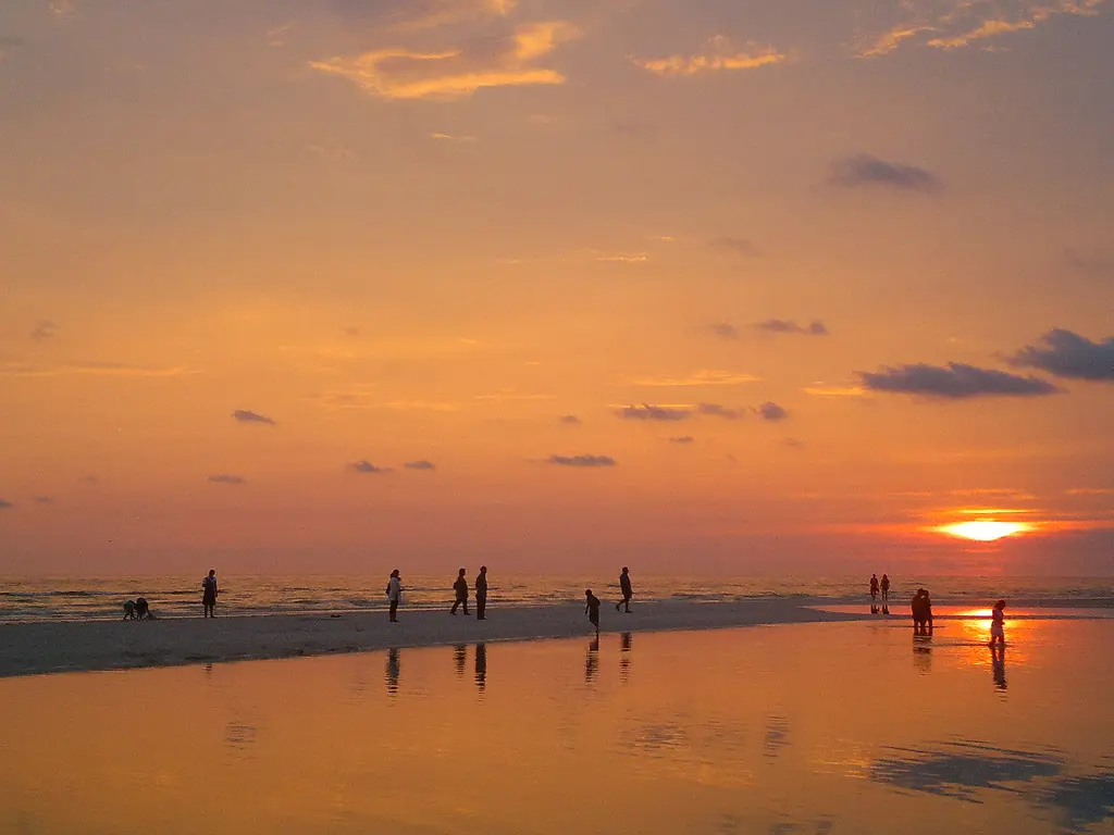 Visitors exploring a shoreline tide pool at sunset in Honeymoon Island State Park