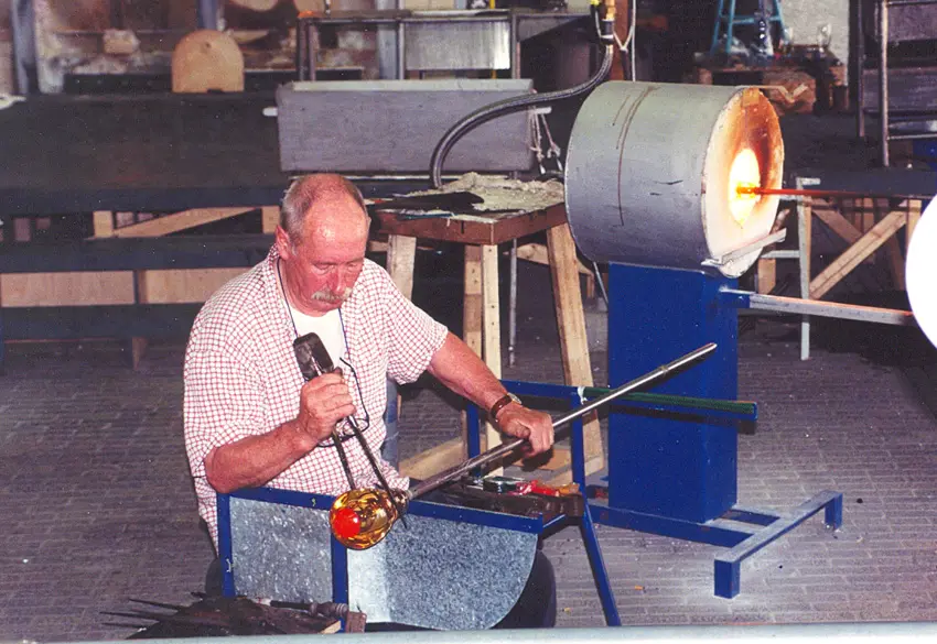 Glass artist shaping molten glass during a blowing demonstration, representative of the Morean glass experience