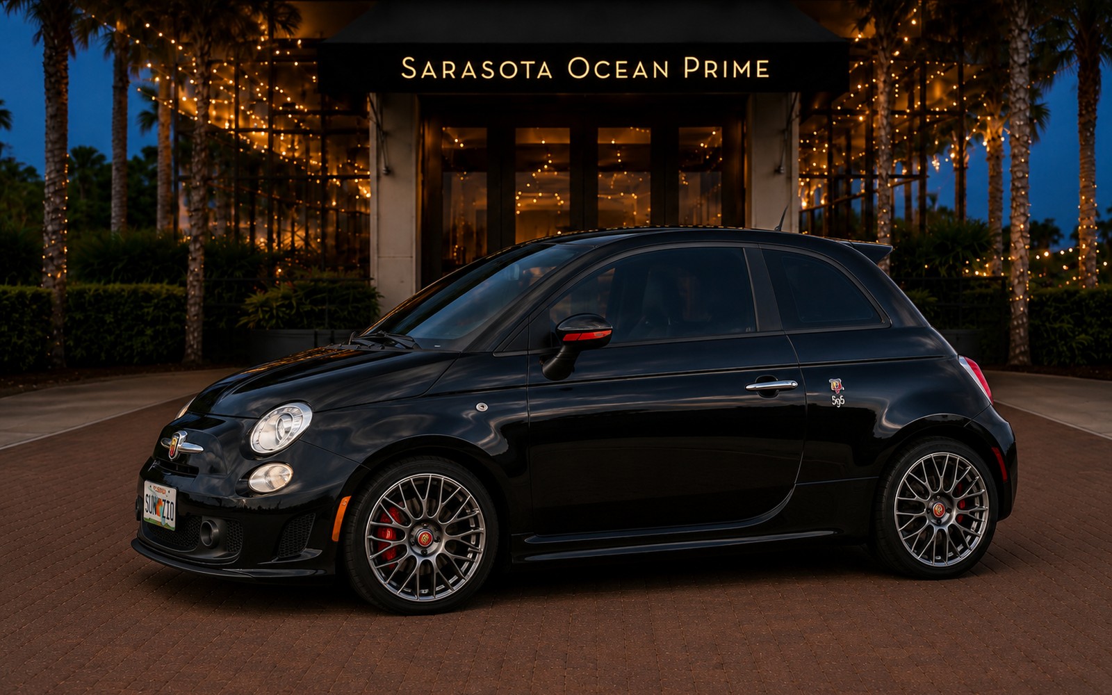 Black Fiat 500 Abarth rental parked at Sarasota Ocean Prime in the evening