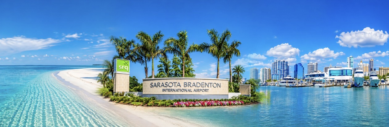 Sarasota Bradenton International Airport sign between a white-sand beach and Sarasota marina
